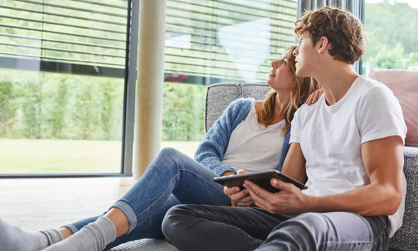 Man en vrouw kijken naar elektrische jaloezieën van Busch-Jaeger