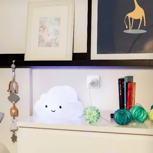 Ein Nachttisch mit einer Wolkenlampe, einem Buch, Dekorationselementen und einem Schlafzimmer mit einem Kissen.