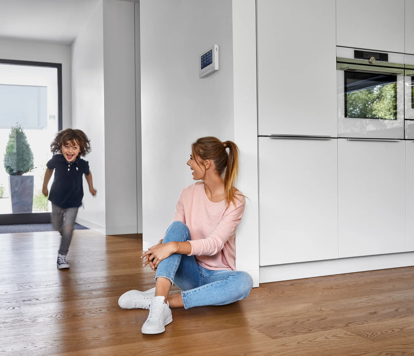 Frau und Kind sitzen in der Küche auf dem Holzboden