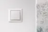 Weißer Lichtschalter an einer Wand.